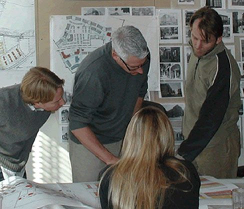 A close-up of two men and a woman looking at a project blueprint.